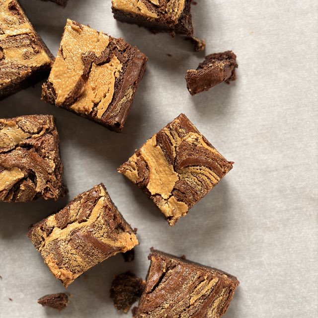 Peanut butter swirl brownies cut into squares on parchment